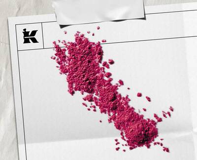 Bright pink powder pigment scattered across whitepaper packaging featuring the Kiehl’s logo.