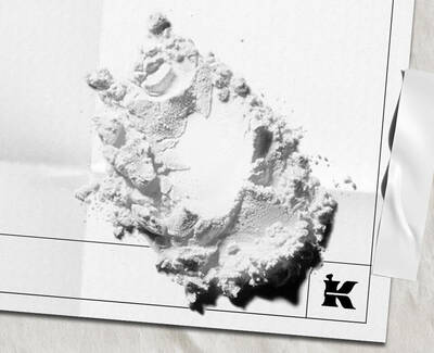White powder ingredient scattered on white paper packaging with the Kiehl’s logo.
